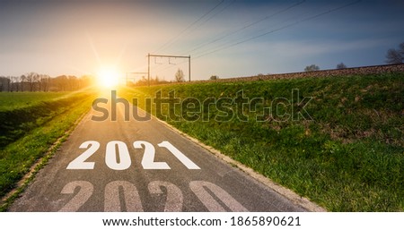 New Year's concept with year 2021 printed in the middle of an asphalt road at sunset. Way to success, opportunities and possibilities, business and personal.