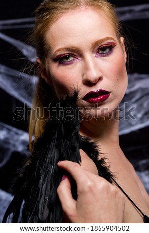 
Woman dressed in elegant way as witch for Halloween party with black background and spider webs