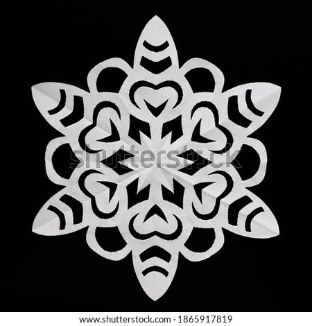 Paper snowflake on black background, close-up. Handmade new year decoration