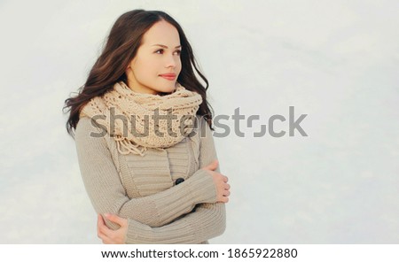 Portrait of lovely young brunette woman wearing a knitted scarf, sweater outdoors