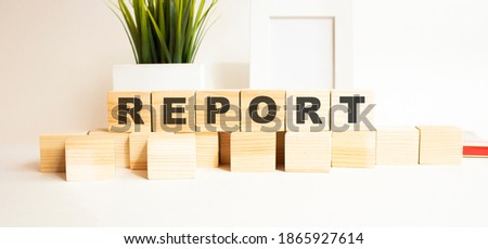Wooden cubes with letters on a white table. The word is REPORT. White background.
