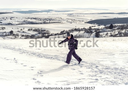 Happy little girl is playing with snow in park on white snow background