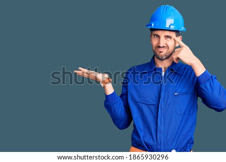 Young handsome man wearing worker uniform and hardhat rubbing eyes for fatigue and headache, sleepy and tired expression. vision problem 
