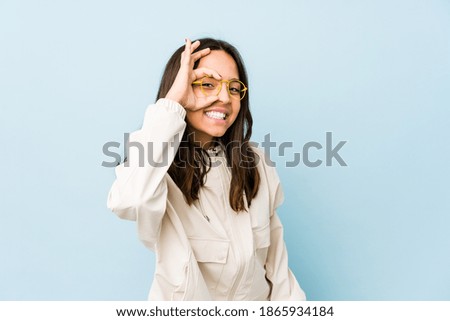 Young mixed race hispanic woman isolated excited keeping ok gesture on eye.