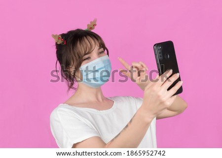 Woman wearing protective face mask and video call for Christmas. New celebration concept. Pink background. High quality photo