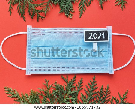 Christmas concept face mask on red background with fir borders. Covid new year 2021 celebration. 