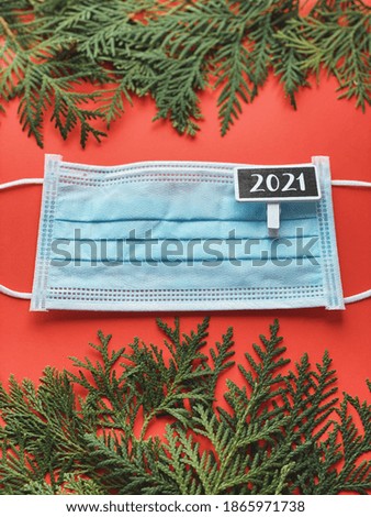 Christmas concept face mask on red background with fir borders. Covid new year 2021 celebration. 