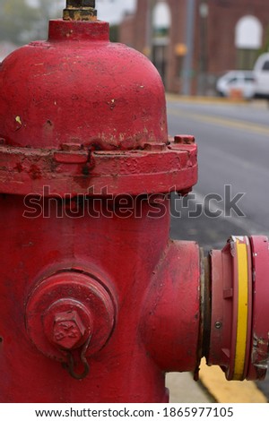 Extreme close-up of a red fire hydrant that dominates the frame on three sides, showing age, yet well maintained.  Background shows a road.