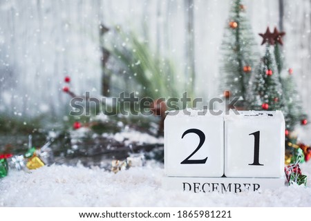 Winter Solstice. White wood calendar blocks with the date December 21st and Christmas decorations with snow. Selective focus with blurred background. 