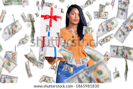 Hispanic woman with long hair holding gifts thinking attitude and sober expression looking self confident