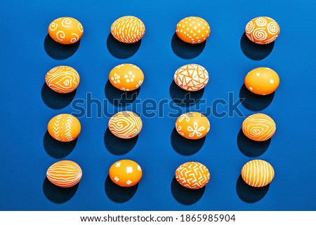 Orange colored Easter eggs pattern on contrasting blue background.