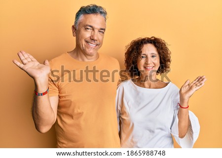 Beautiful middle age couple together wearing casual clothes smiling cheerful presenting and pointing with palm of hand looking at the camera. 