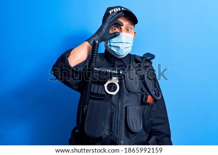 Senior police man wearing surgical mask smiling happy doing ok sign with hand on eye looking through fingers 