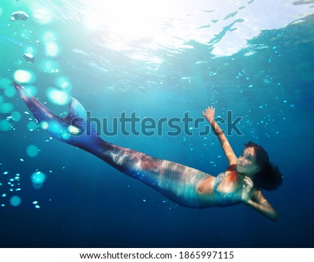 Portrait of a girl mermaid with tail swim under water in the ocean
