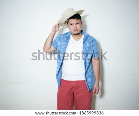 Studio shot of happy tourist man smiling while wearing hat 
In a white background.
Holiday traveler concept