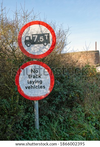 Warning signs for a weight limit and no track laying vehicles on approach to a weak bridge