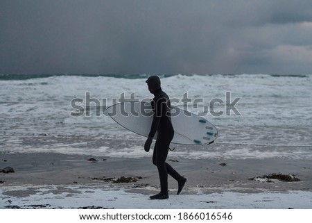 Arctic surfer going by beach after surfing