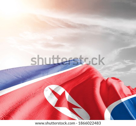 Korea, North national flag cloth fabric waving on beautiful grey sky.