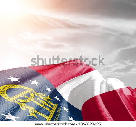 Georgia national flag cloth fabric waving on beautiful grey sky.
