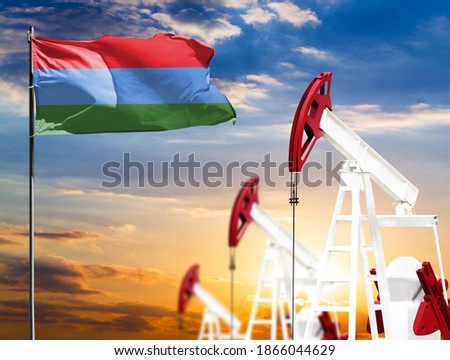 Oil rigs against the backdrop of the colorful sky and a flagpole with the flag of Karelia. The concept of oil production, minerals, development of new deposits.