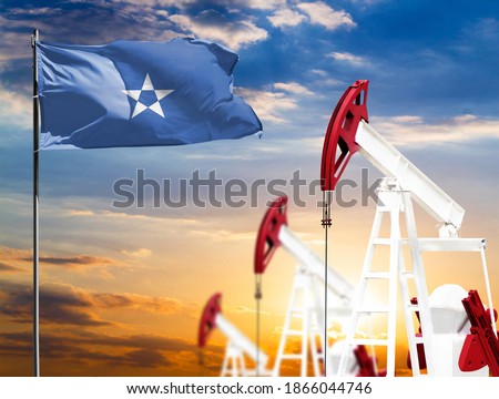 Oil rigs against the backdrop of the colorful sky and a flagpole with the flag of Somalia. The concept of oil production, minerals, development of new deposits.