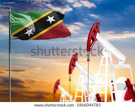Oil rigs against the backdrop of the colorful sky and a flagpole with the flag of Saint Kitts and Nevis. The concept of oil production, minerals, development of new deposits.
