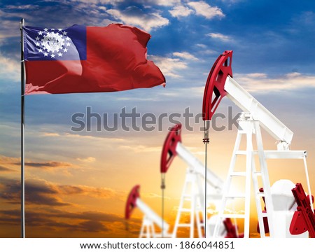 Oil rigs against the backdrop of the colorful sky and a flagpole with the flag of Myanmar Burma. The concept of oil production, minerals, development of new deposits.