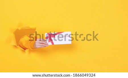 Close up cropped woman hand hold gift certificate card coupon voucher on birthday holiday party or store isolated through torn yellow background studio. Copy space text place. Advertising area mock up Royalty-Free Stock Photo #1866049324