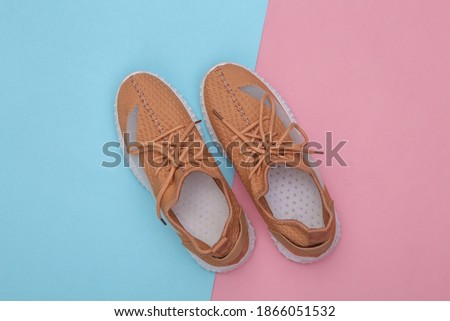 Brown textile sports shoes on a blue-pink pastel background. Top view