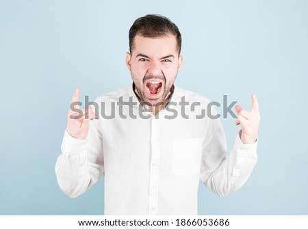 Man shouting with crazy expression doing rock symbol with hands up. Heavy concept.