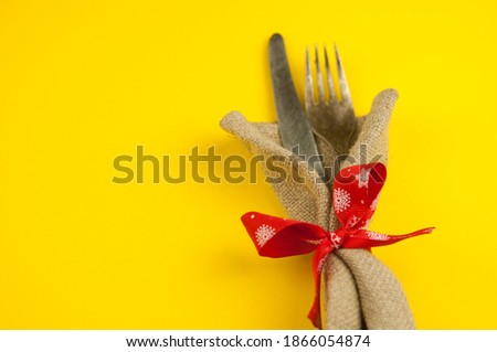 Christmas place setting with vintage silverware in napkin and ribbon on yellow background with copy space for your text or words. Top vie