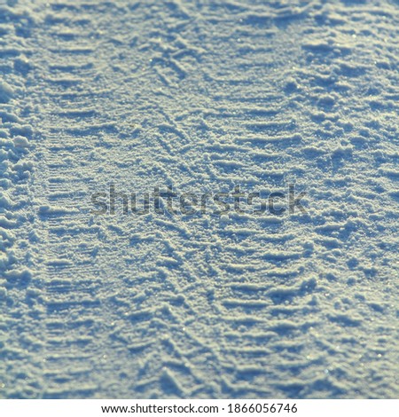 Tire tracks left in the snow on a bright sunny day. The concept of snow removal, ski resorts, active winter vacations. Stock photo with empty space for text and design