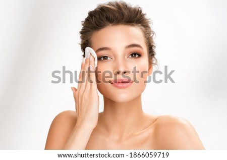 Woman removing makeup, holds cotton pads near face. Photo of woman with perfect skin on white background. Beauty and skin care concept
