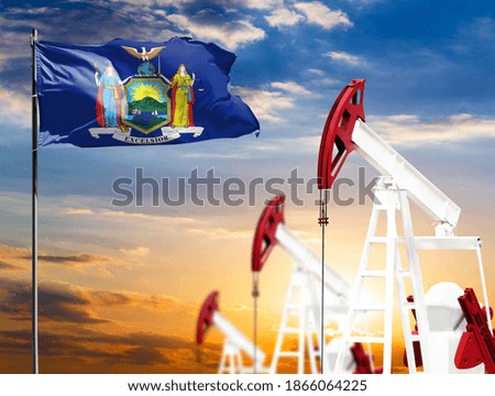 Oil rigs against the backdrop of the colorful sky and a flagpole with the flag State of New York. The concept of oil production, minerals, development of new deposits.
