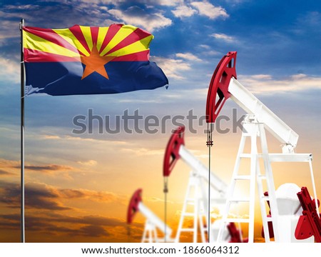 Oil rigs against the backdrop of the colorful sky and a flagpole with the flag State of Arizona. The concept of oil production, minerals, development of new deposits.