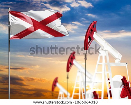 Oil rigs against the backdrop of the colorful sky and a flagpole with the flag State of Alabama. The concept of oil production, minerals, development of new deposits.