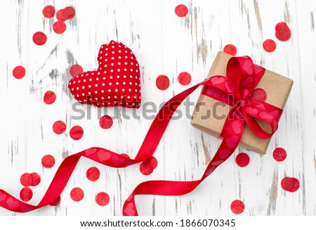 Valentines gift box with a red ribbon and heart shape on white wooden background. Greeting card, banner, copy space