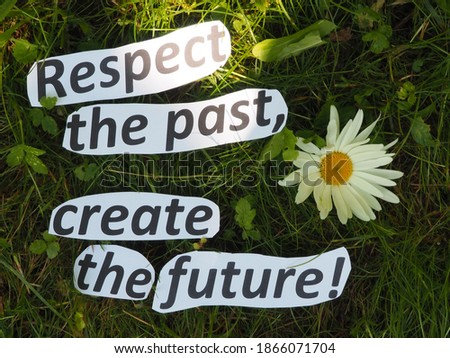 respect the past, create the future. lettering on the grass made of cut out paper letters.