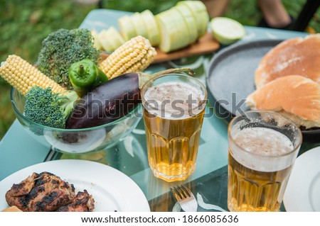 Beer, kebab, vegetables, grill, kebab spread out on the picnic table. A warm summer day and a trip to nature. Photo with no people