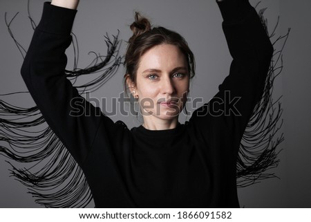 Portrait of young dancing woman looking at the camera. Isolated on white wall.