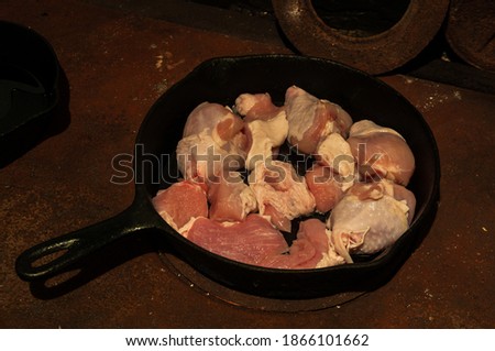 prepare meat in a cast-iron frying pan standing on a rusty wood-burning stove. High quality photo