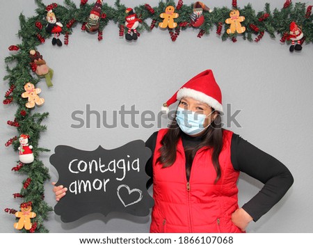 latin woman with santa claus hat and blackboard with message "contagious love" in Christmas decoration