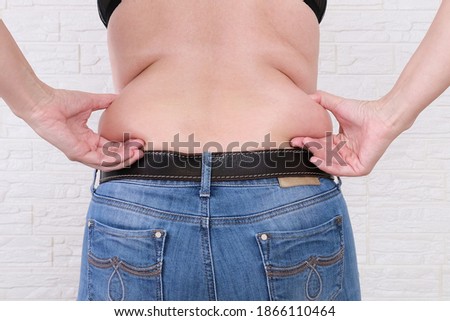 Young woman pinches the fat on the side of her waist to show the flab, overweighted fat body as s result of improper diet. Royalty-Free Stock Photo #1866110464