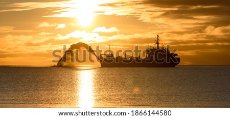 Vessel engaged in dredging at sunset time. Hopper dredger working at sea. Ship excavating material from a water environment. Beautiful sunset. Royalty-Free Stock Photo #1866144580
