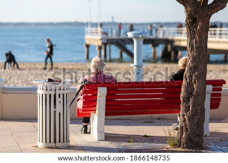 people sitting on a bench looking at the sea