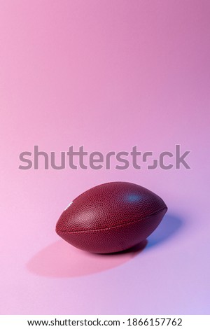 American Football ball on pink background. Spot team concept