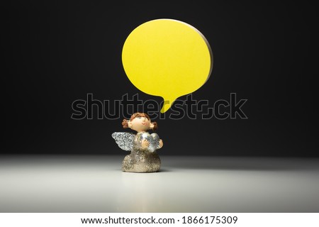 Small Child Angel Holding A Heart With a Yellow Bubble Talk Balloon On Dark Background