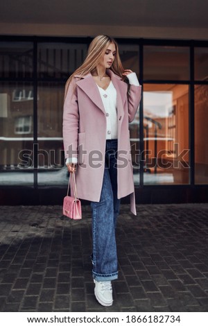 Stylish blonde girl posing against the backdrop of a building. Image photo session.