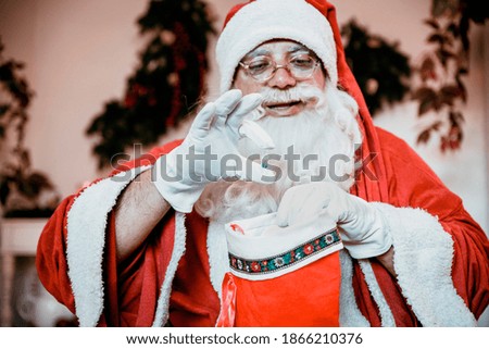 Santa Claus holding New Vaccine for Coronavirus. Vaccine dose delivery as Christmas Gift in big red Sock