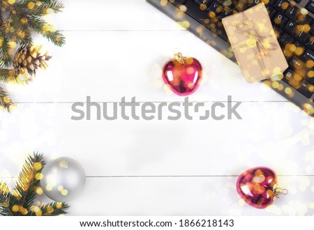 Keyboard, gift box, fir branches, balls on a white wooden background. Online shopping. Ordering gifts on the Internet. Flat lay.
